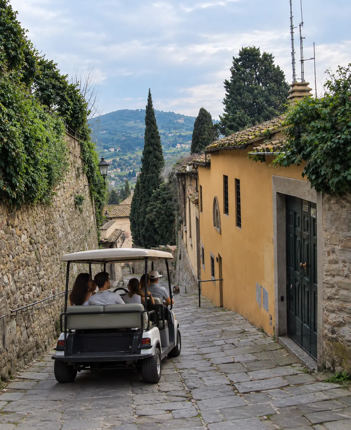 Golf cart descending a stone lane surrounded by Tuscan buildings in Fiesole