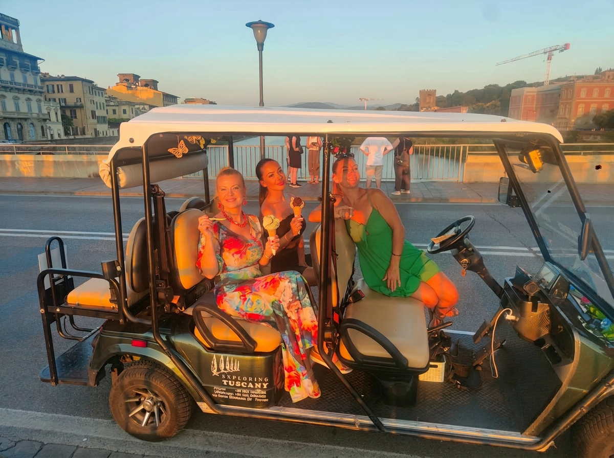 Three guests in the AirStar golf cart with gelato cones along the Arno at sunset
