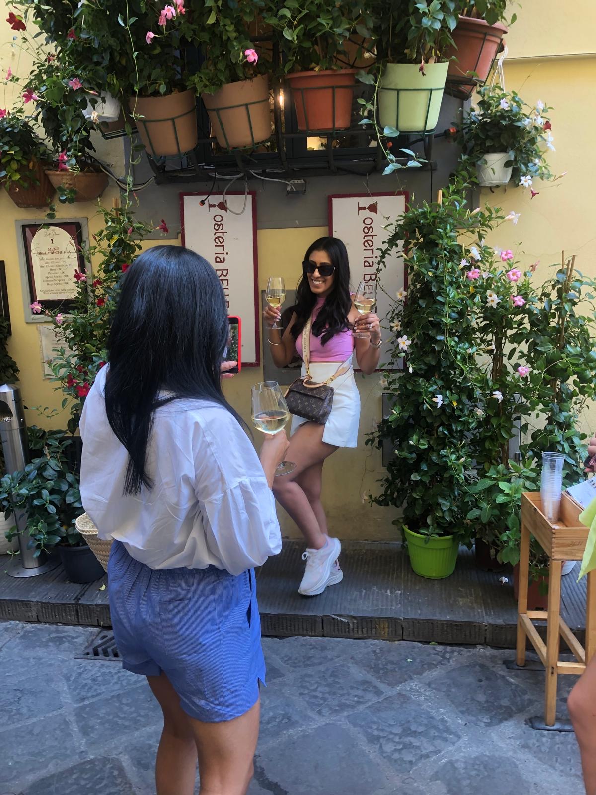 Guest posing with two glasses of Tuscan white wine at the wine window